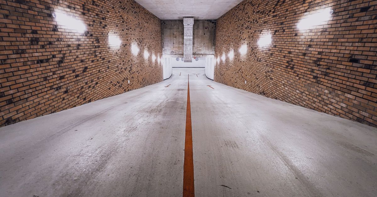 An underground brick-walled ramp with dim lighting and a single yellow line, creating a cinematic feel.