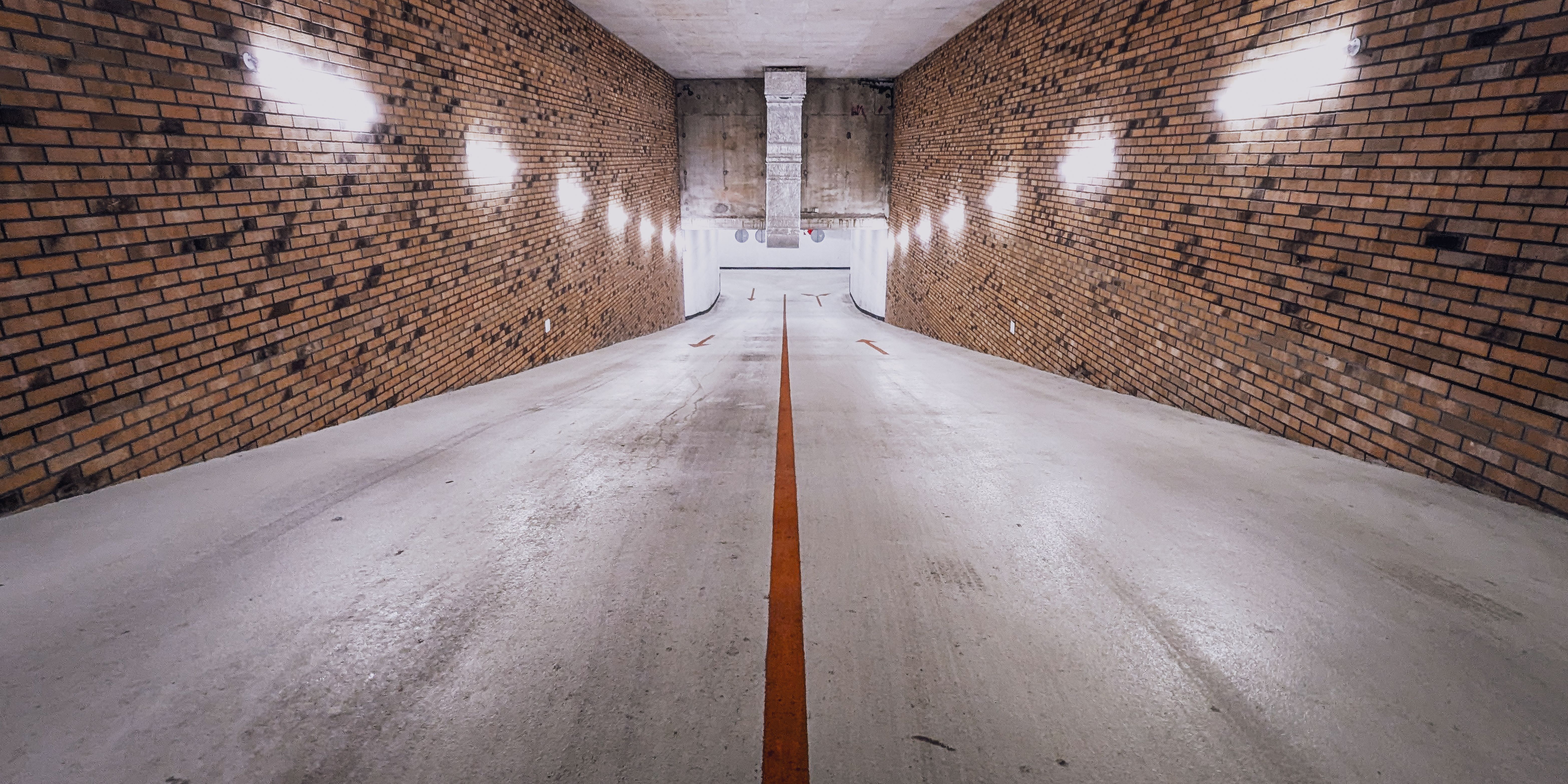 Dimly Lit Underground Parking Ramp with Brick Walls · Free Stock Photo