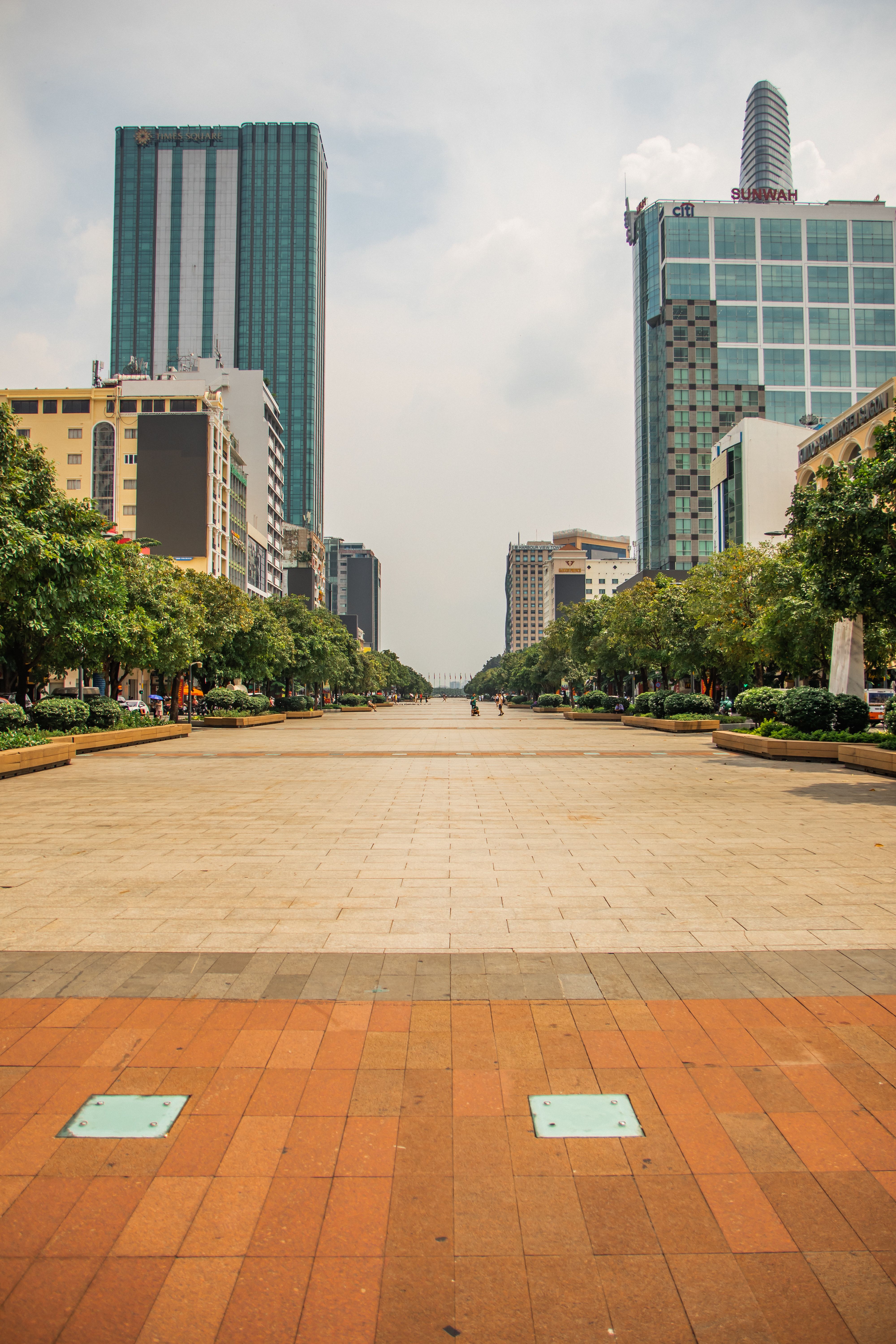 Bustling urban street in Hồ Chí Minh City showcasing modern skyscrapers and lush greenery.
