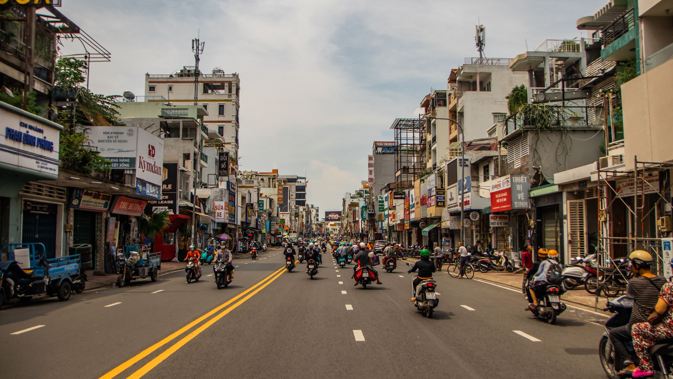 Motorcycles fill a lively street in Ho Chi Minh City, Vietnam, with bustling energy and vibrant architecture.