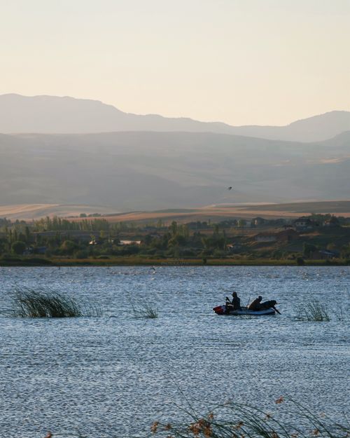 Free Peaceful lake scene in İskilip, Türkiye with a boat and mountains in the background. Stock Photo
