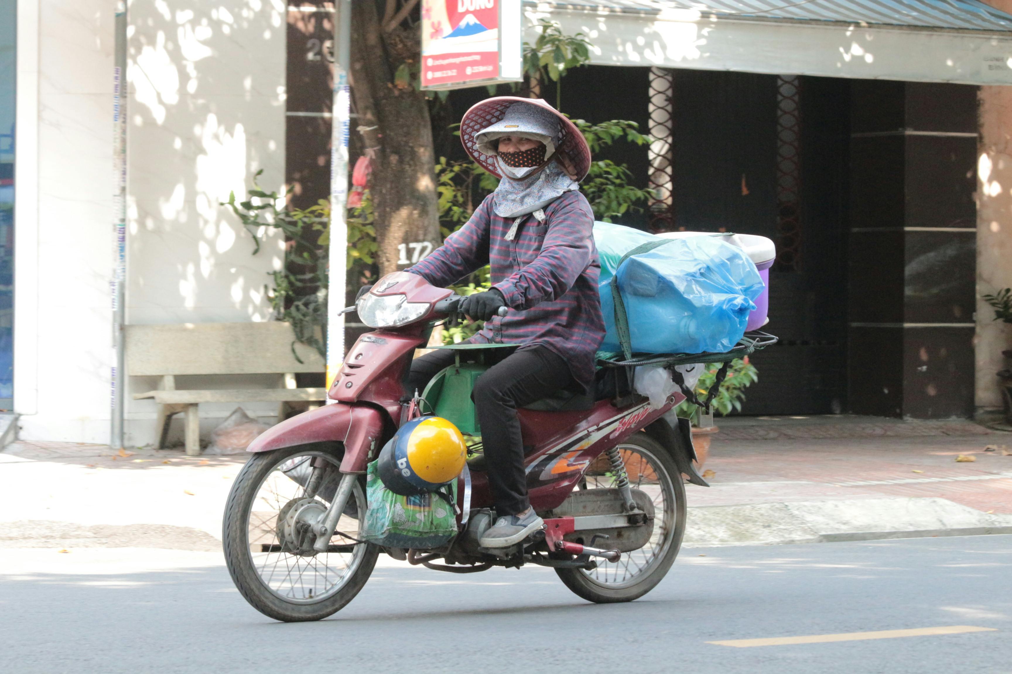 A motorbike rider transported goods in sunny Ho Chi Minh City street scene.