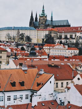 Explore the historic charm of Prague with this stunning view of Prague Castle and red rooftops.