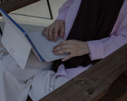A woman in a hijab using a tablet outdoors, captured in İstanbul.