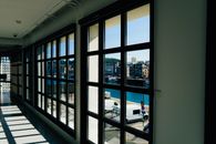 Spacious corridor with large windows overlooking a vibrant urban cityscape.