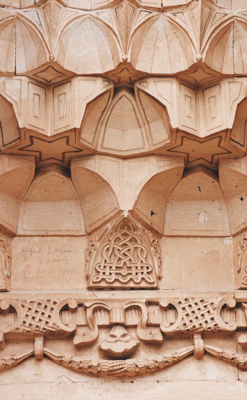 Free Detailed view of Islamic architectural stonework showcasing geometric and floral patterns. Stock Photo