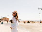 一位时尚女士戴着墨镜，在晴朗的天空下，悠闲地沿着科尼岛木板路漫步