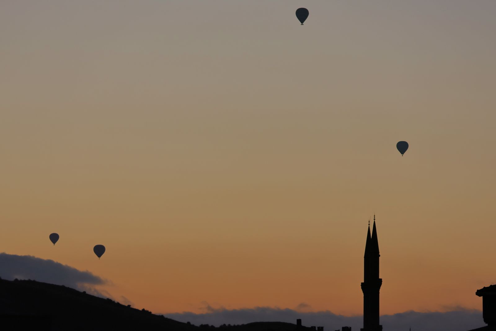 Hot-air balloons drifting over a valley at sunrise — photo by Sena on Pexels