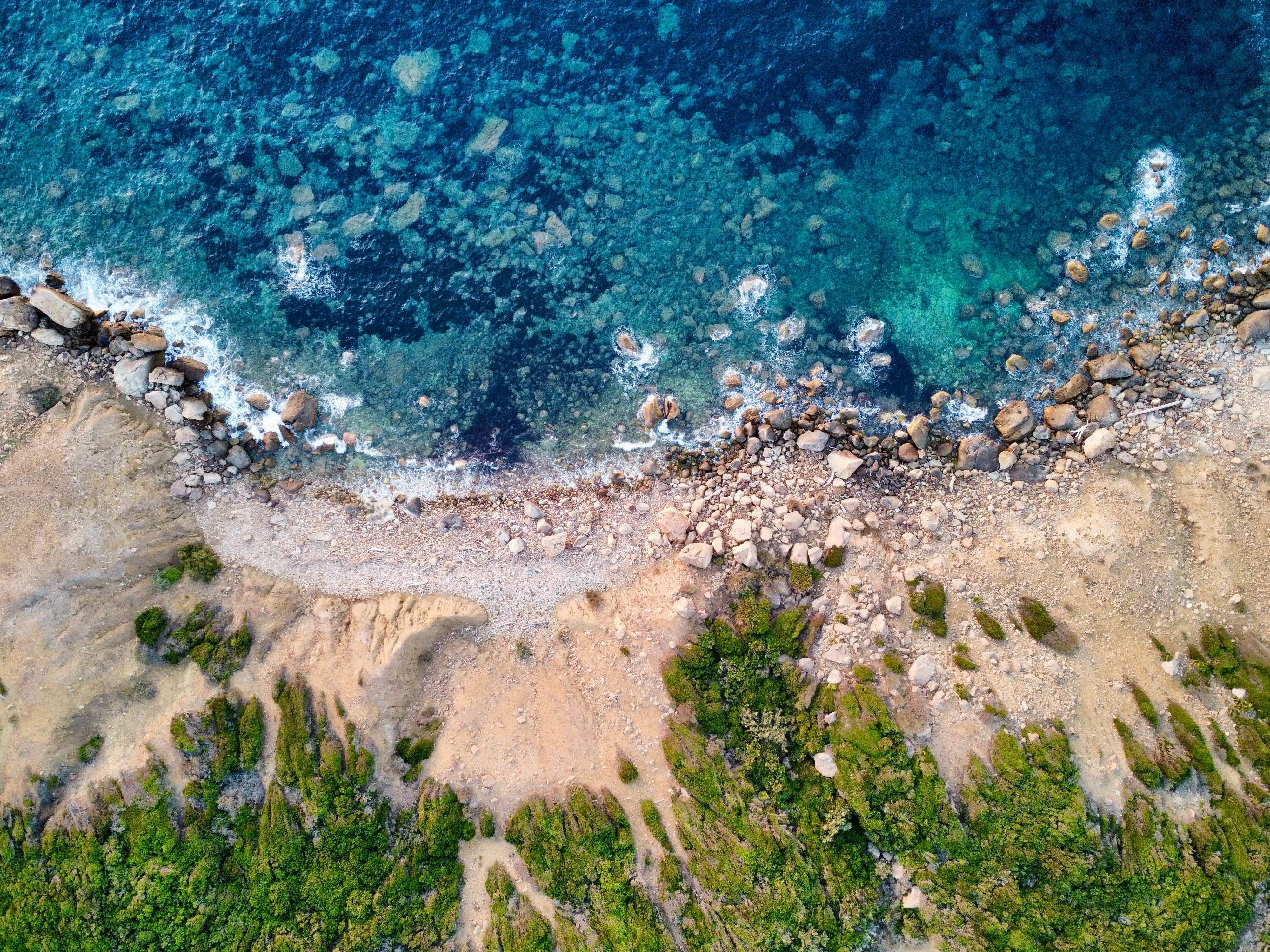 Aerial View of Rocky Coastline and Clear Blue Sea · Free Stock Photo