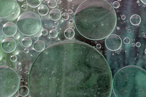 Free Close-up of green oil bubbles on water creating an abstract pattern. Stock Photo