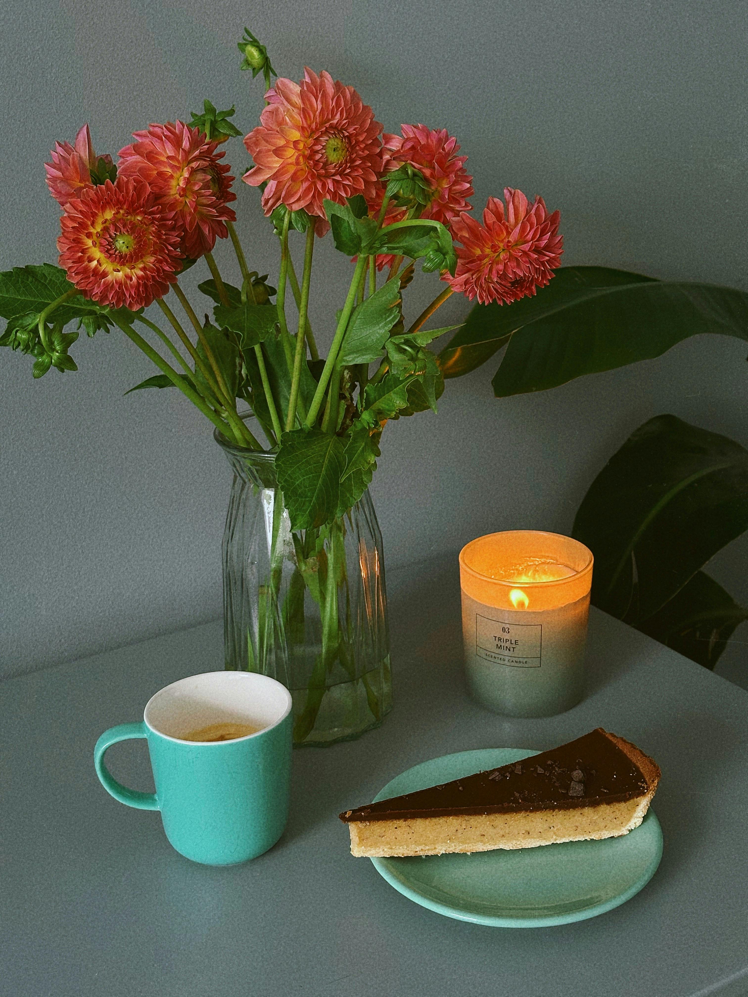 A charming still life with flowers, cake, candle, and coffee.
