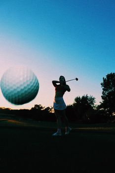 Dynamic shot of a golfer teeing off with a close-up of a golf ball at sunset.