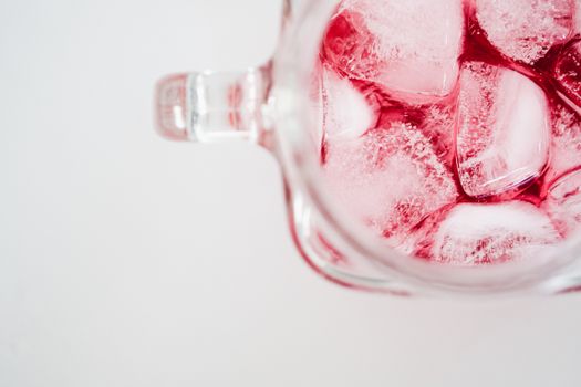 Top view of a refreshing iced red drink in a transparent glass mug. Perfect for summer.