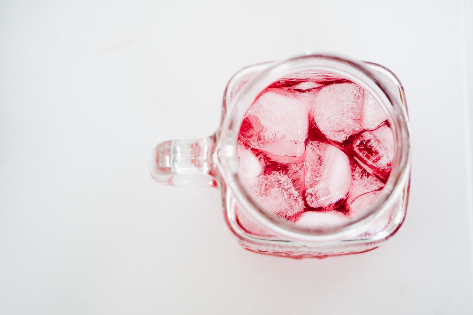 Top view of a refreshing iced red fruit beverage in a mason jar, perfect for summer.