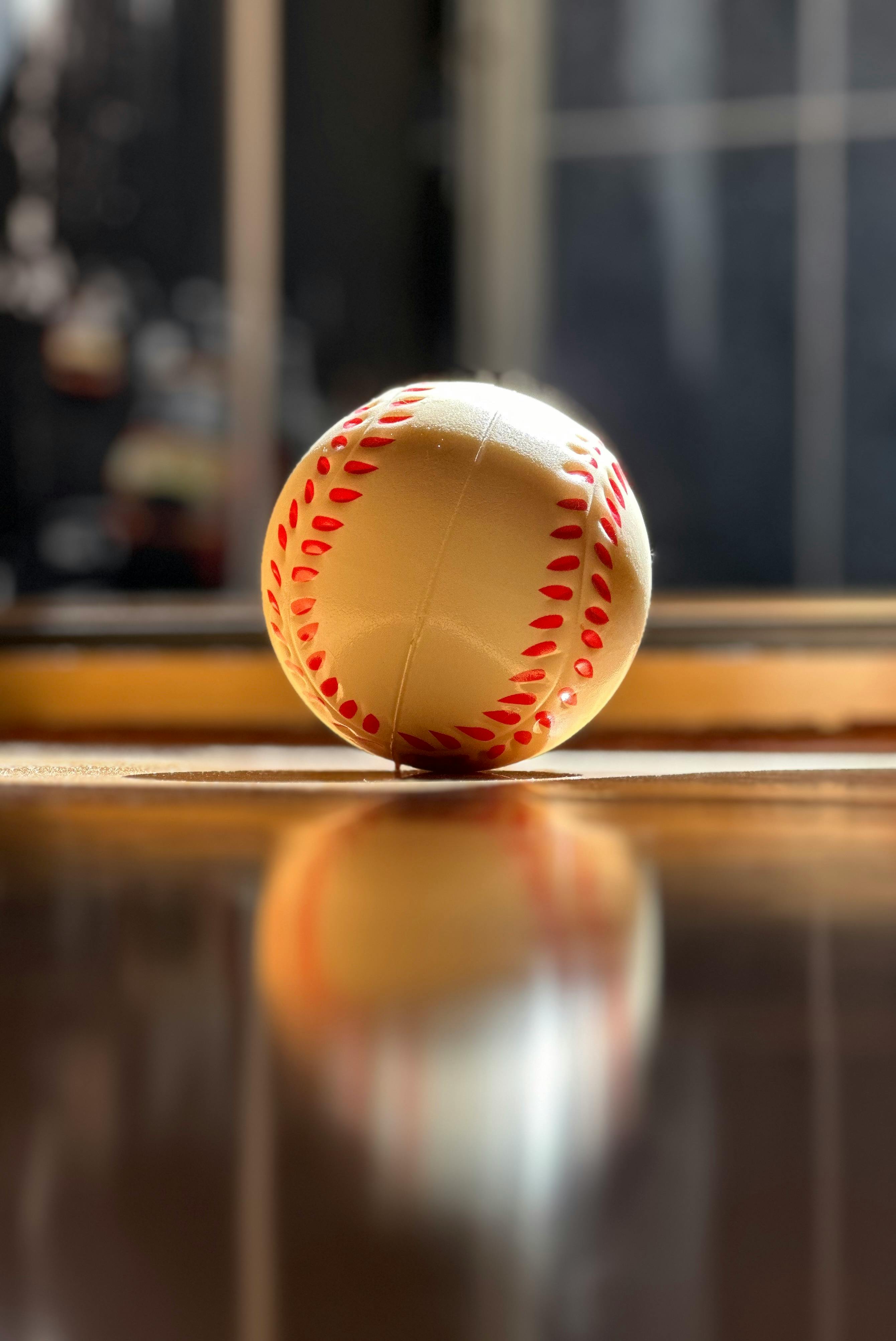 close up of baseball with shadows on wooden floor