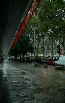 Street in Barcelona soaked after rain, capturing urban life with reflections on wet pavement.