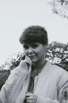 Black and white portrait of a woman with short hair, posing outdoors in fall.