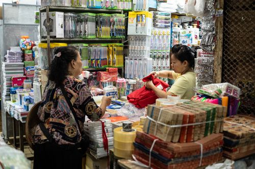 Free Women interacting in a bustling Dong Xuan Market shop filled with household goods in Hanoi, Vietnam. Stock Photo