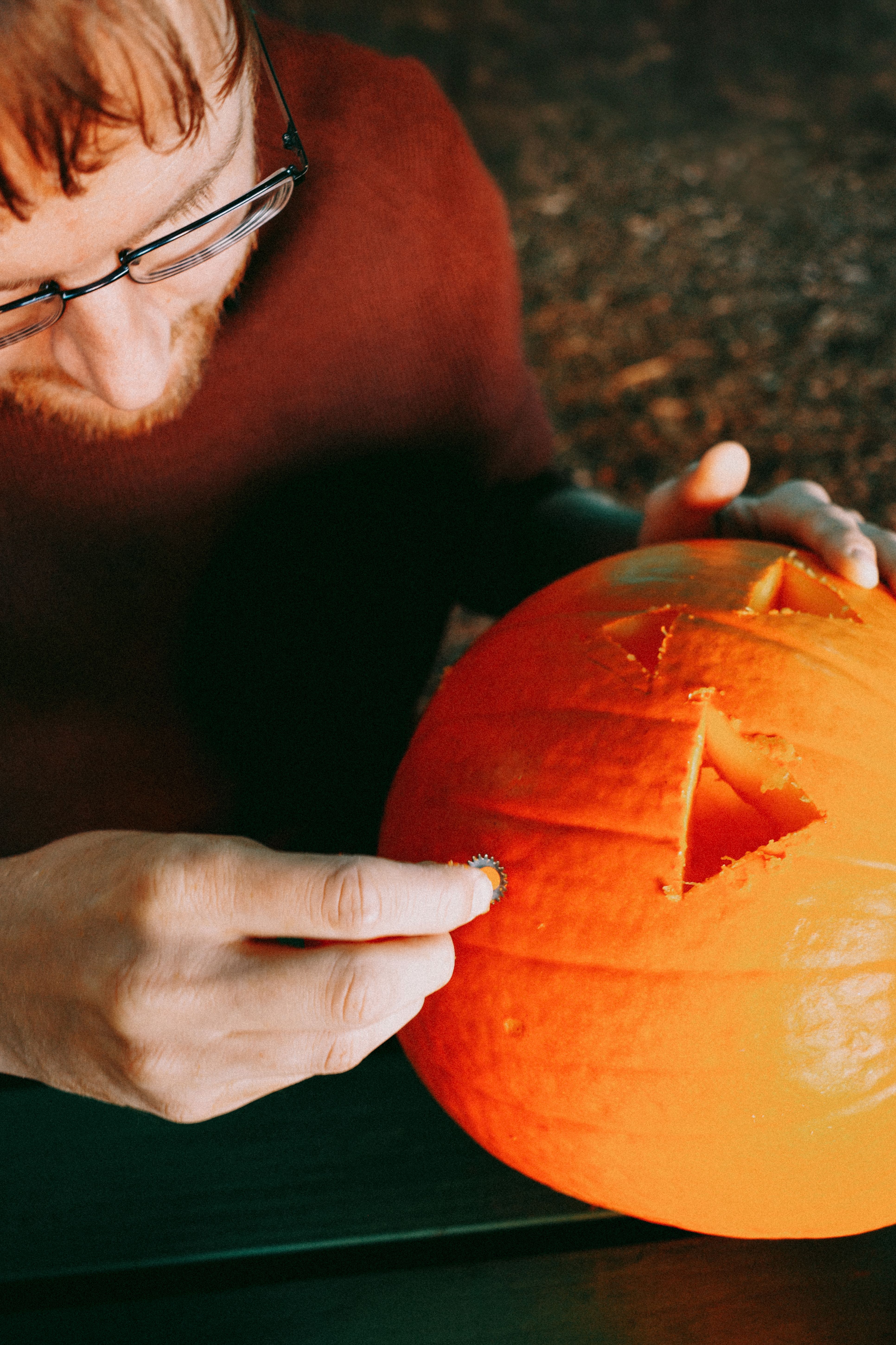 Close-up of a man carving a jack-o'-lantern for Halloween festivities.