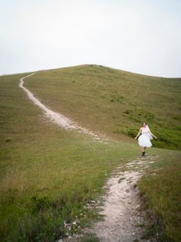 A bride in a white dress strolls along a scenic path in Vietnam's lush countryside.