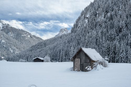 Free Serene winter landscape featuring a snowy cabin in the Canazei region of the Dolomites, Italy. Stock Photo