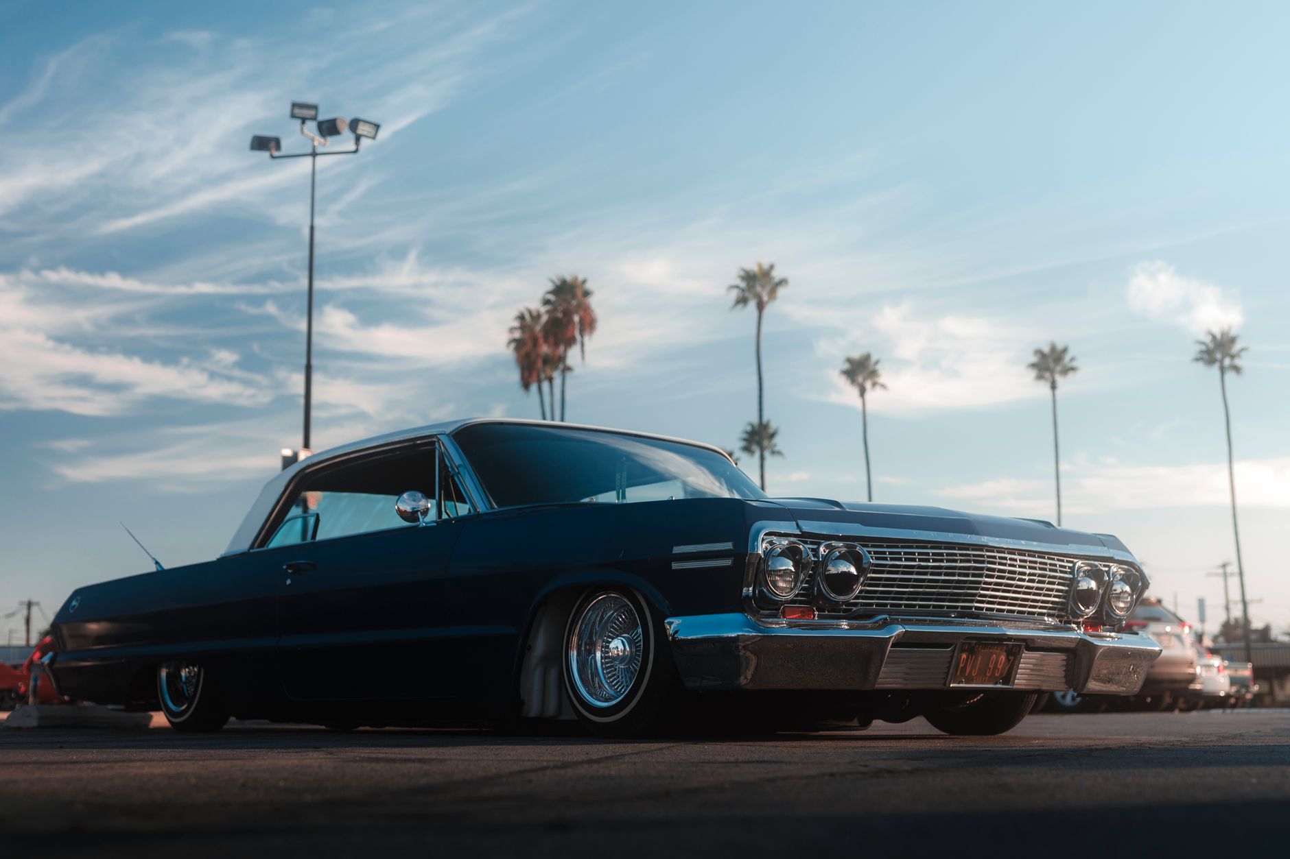 Vintage auto met palmbomen in een zonnige Californische omgeving onder een heldere lucht.