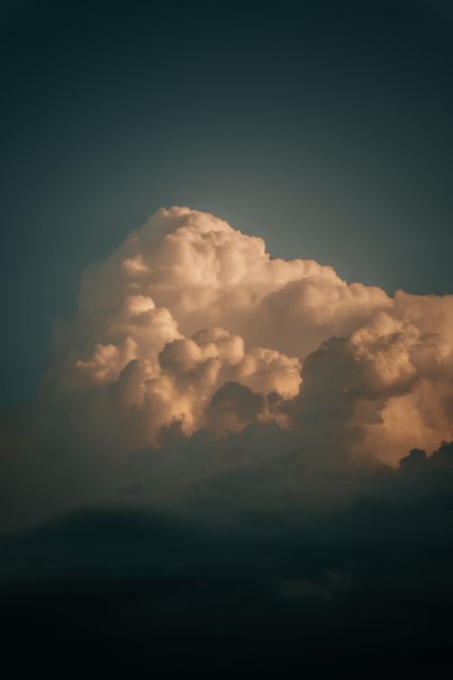 Free A striking cumulonimbus cloud illuminated in dramatic twilight tones against a darkening sky. Stock Photo