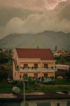 Charming two-story house set against misty mountains, showcasing serene outdoor scenery.