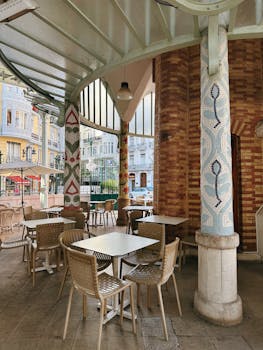 Charming outdoor cafe with colorful mosaic columns and wicker chairs.