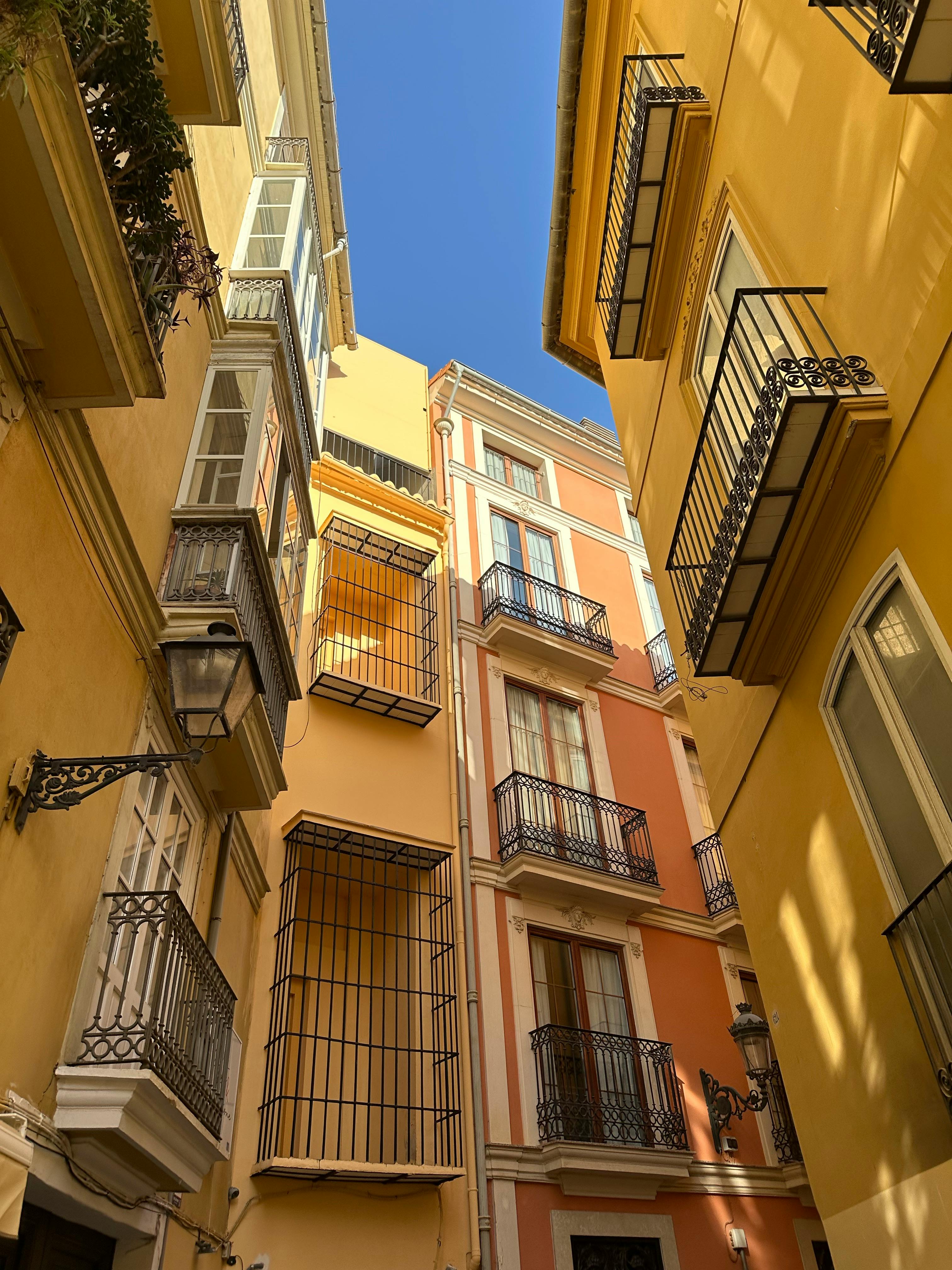 Vibrant Spanish alleyway with colorful facades and wrought iron balconies.