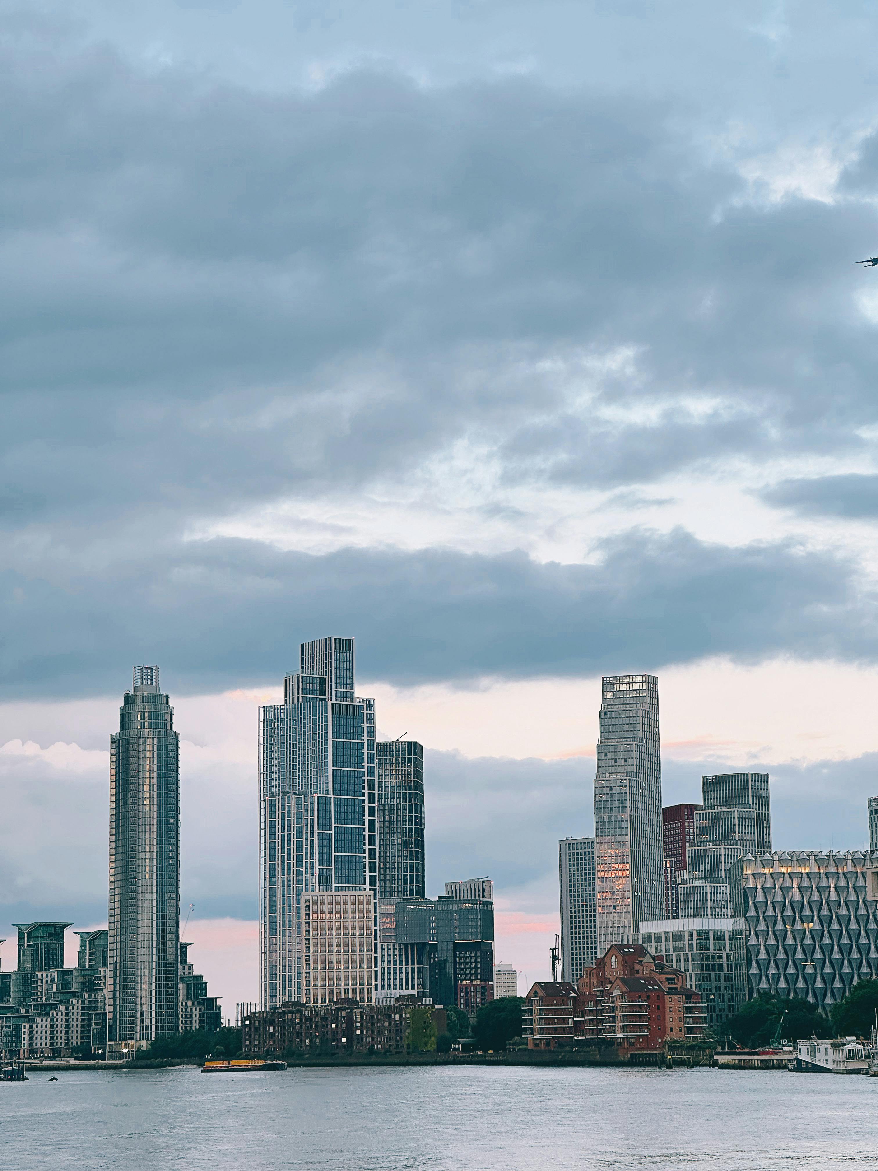 Serene view of London's skyline with towering skyscrapers and cloudy sky.