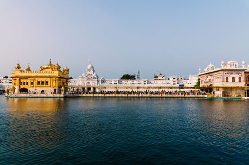 Free The stunning Golden Temple in Amritsar reflecting beautifully on serene water under a clear blue sky. Stock Photo