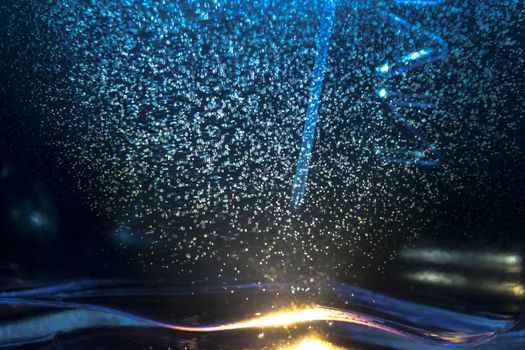 Abstract image capturing bubbles illuminated by blue light, creating a mesmerizing pattern.