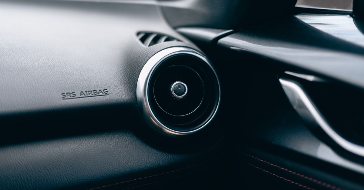 Close-up of a car interior featuring an air vent and SRS airbag text on the dashboard.