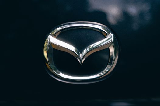 Close-up of a shiny metallic car logo on a dark surface.