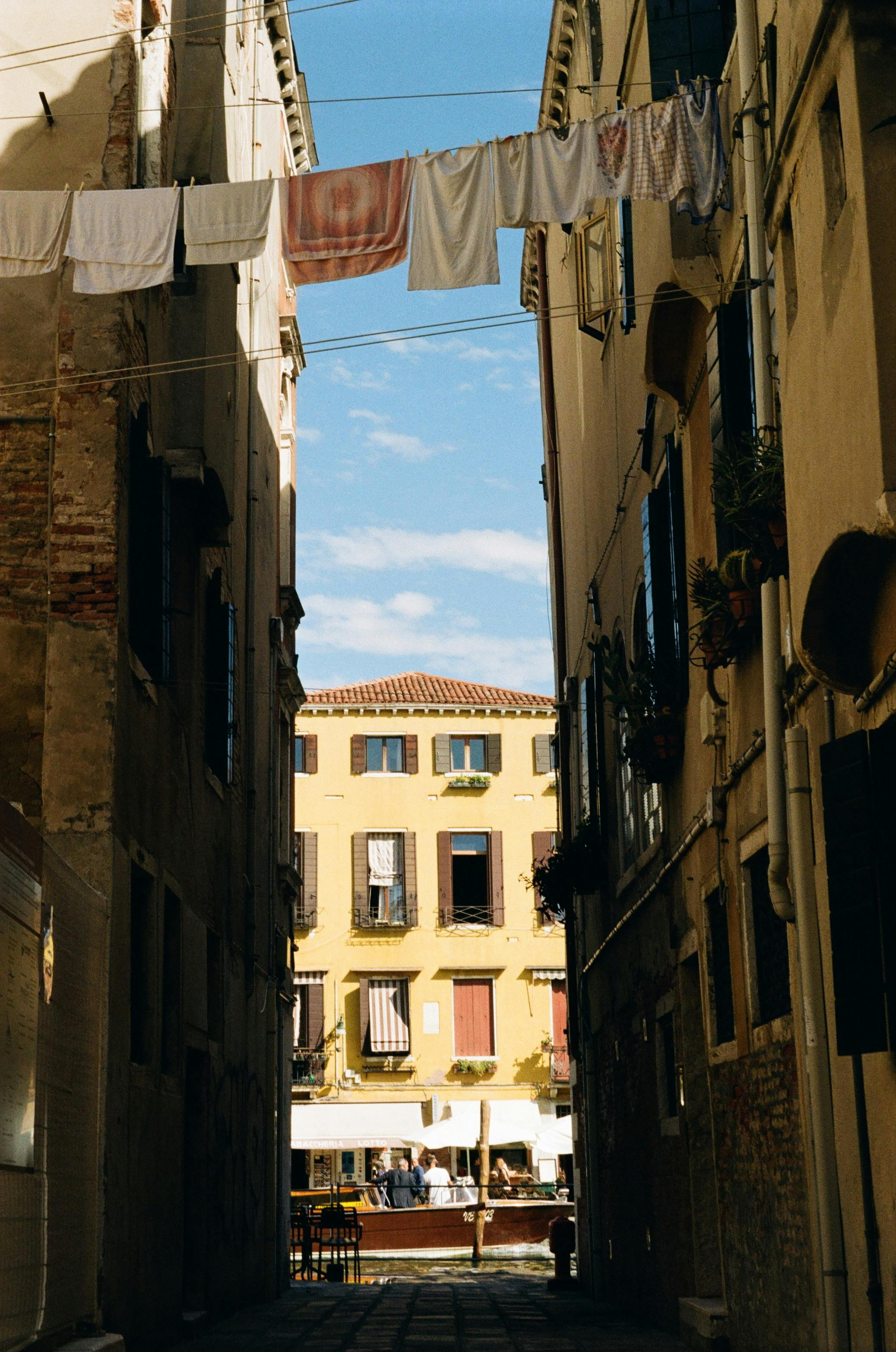 Quaint Venice street view with laundry hanging between narrow buildings.