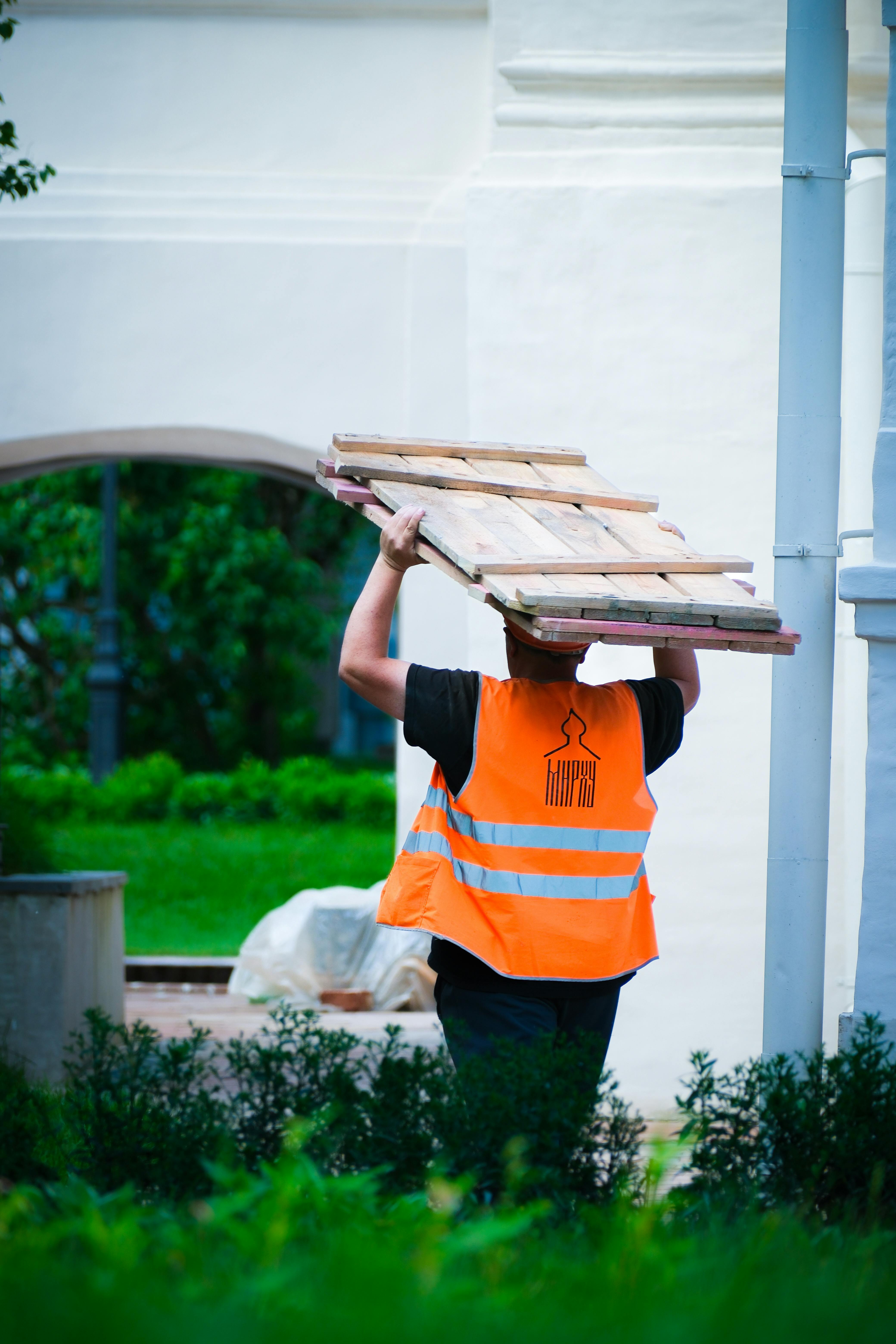 construction worker carrying lumber outdoors