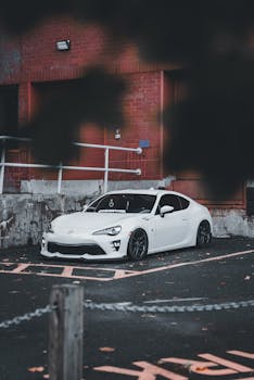 Stylish white sports car parked in an urban setting, highlighting sleek design and modern architecture.