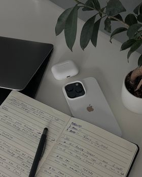 Organized workspace featuring a notebook, smartphone, and laptop.