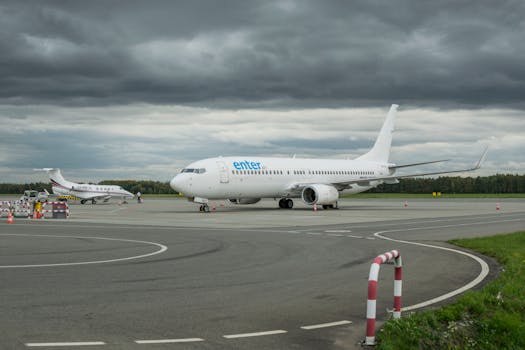 Two airplanes parked on the runway at Wrocław Airport, under cloudy skies.