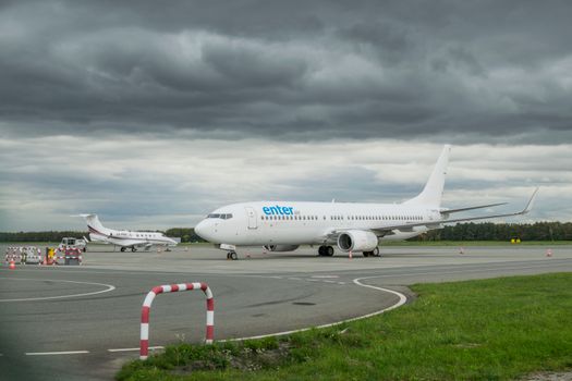 A commercial airplane taxiing on a runway at Wrocław Airport under cloudy skies.
