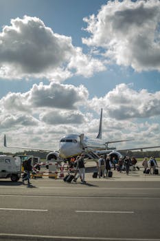 Travelers boarding a passenger plane at Wrocław airport on a clear day.