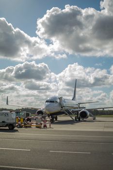 Airplane on the runway at Wrocław Airport beneath a partly cloudy sky.