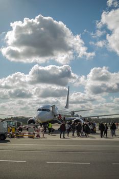 People boarding a commercial airplane at Wrocław Airport under a bright blue sky.