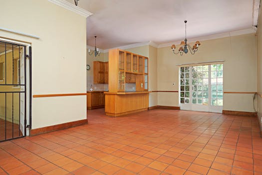 A large, airy kitchen space featuring terracotta tiles and wooden cabinetry awaiting decoration.