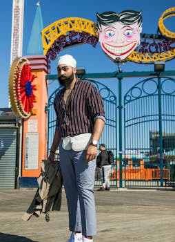 在一个阳光明媚的日子里，一位戴着头巾的时尚男子在科尼岛标志性的入口处摆着姿势