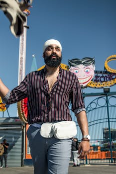 阳光明媚的日子里，一名头戴头巾、留着胡子的男子在科尼岛游乐园时尚地摆着姿势