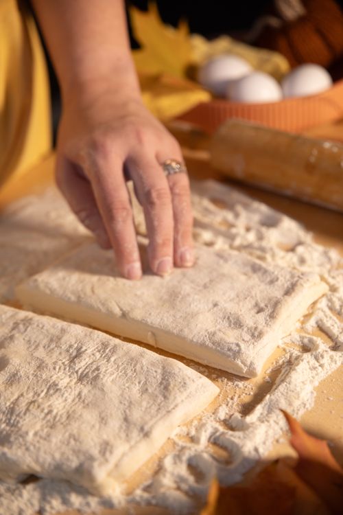Free A baker's hand shaping dough on a floured surface, ready for baking preparation. Stock Photo