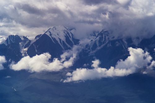 Free Clouds envelop majestic snowy mountain peaks, creating a dramatic scene. Stock Photo