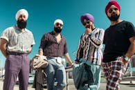 一位头戴方巾的时尚男士在充满活力的户外环境中自信地摆着姿势